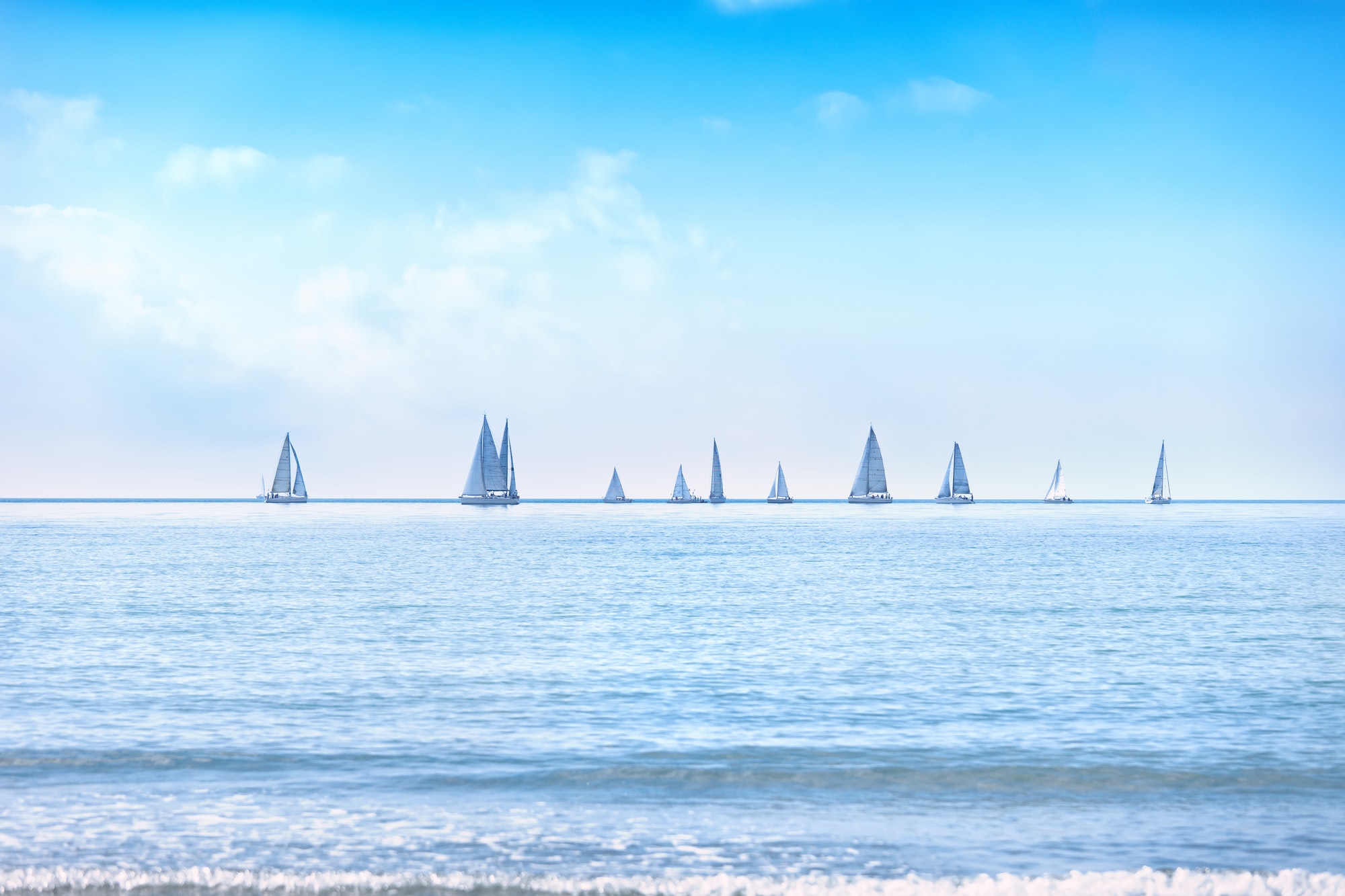 Beautiful azure blue lagoon with sailing catamaran yacht boat at anchor. Pure white pebble beach