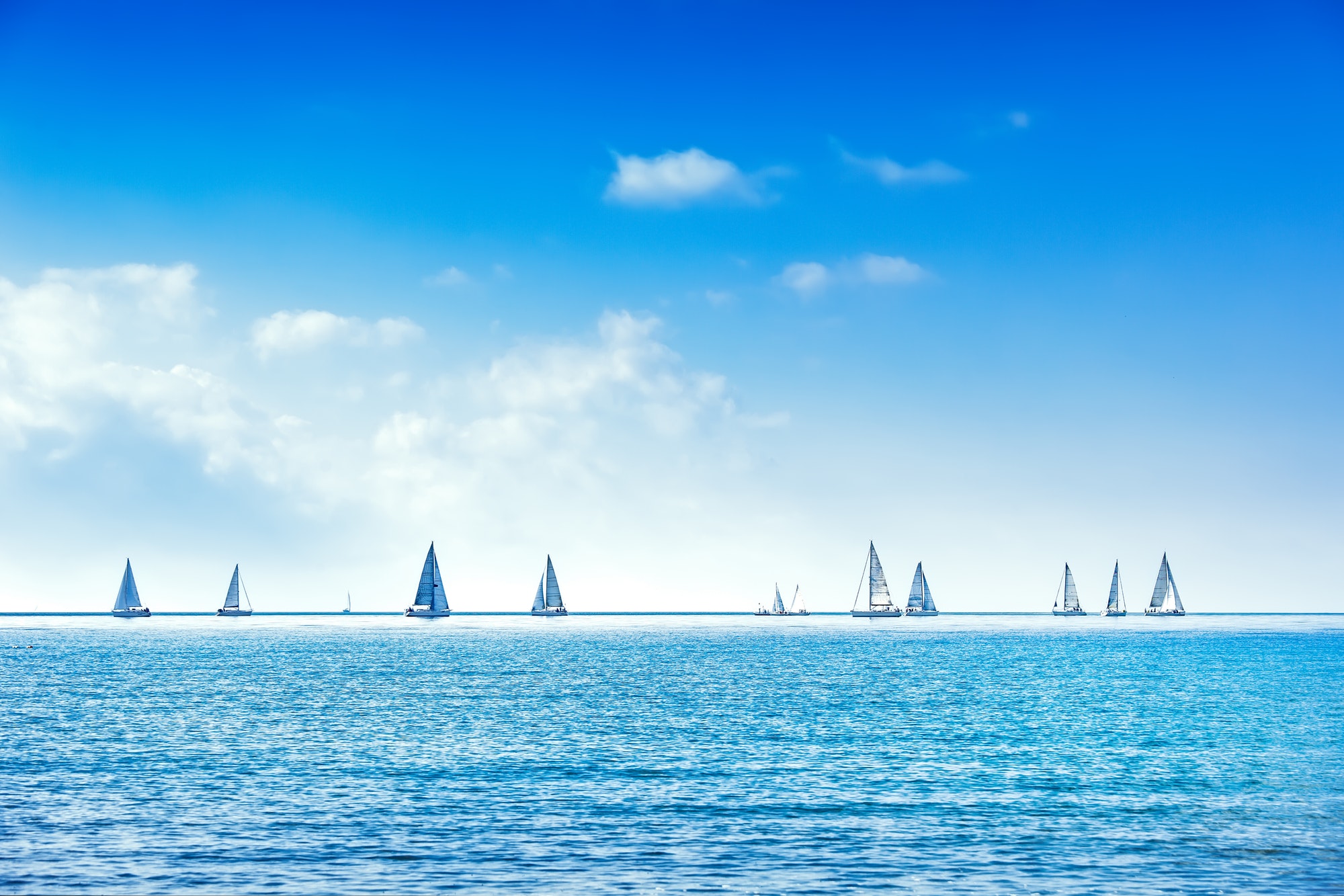 Beautiful azure blue lagoon with sailing catamaran yacht boat at anchor. Pure white pebble beach