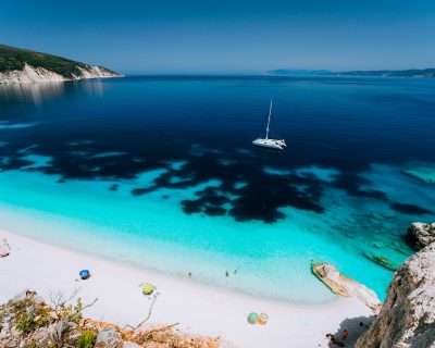 Azure water of Fteri beach, Cephalonia Kefalonia, Greece. White catamaran yacht in clear blue sea